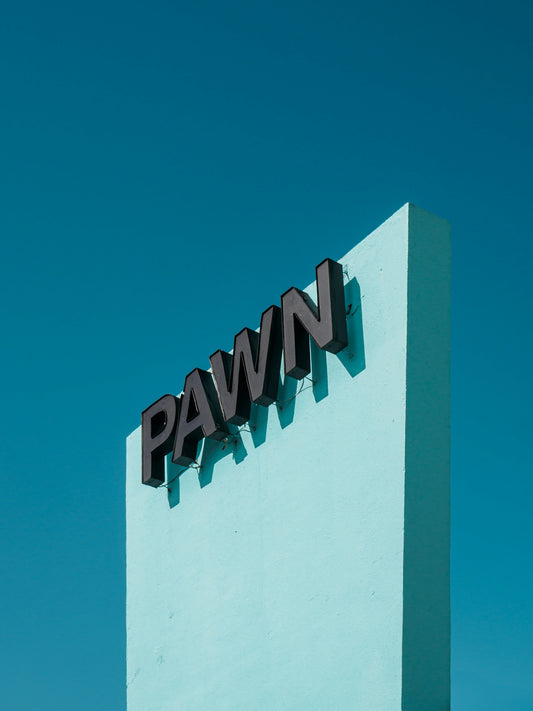 A pawn shop sign against a bright blue sky