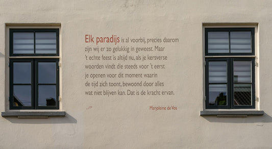 A poem is written on a wall between two windows